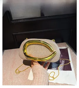 Close-up of champagne glitter clutch bag featuring large gold C-shaped metal handle