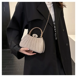 Detail of champagne gold pleated clutch featuring a crown clasp and metal handle