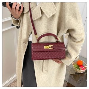 Detail of burgundy woven leather handbag featuring a golden metallic twist lock closure