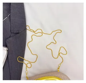 Detailed close-up of the elegant gold chain strap and pearlescent evening clutch bag