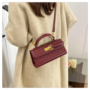Detail of woven burgundy leather handbag with golden metal clasp on beige coat