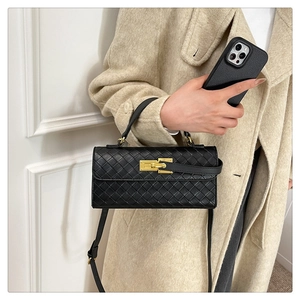 Detail of black woven leather handbag with gold clasp and adjustable shoulder strap