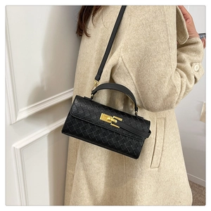 Close-up of black woven texture handbag with gold metal lock on a white coat