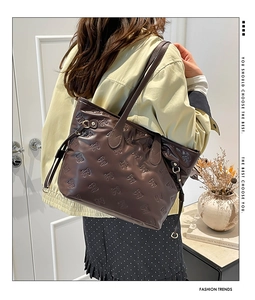 Dettaglio della borsa tote marrone scuro con fiocco goffrato e coulisse laterale