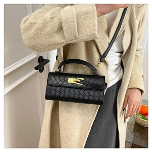 Detail of black woven leather Kelly bag with gold twist lock on beige coat background