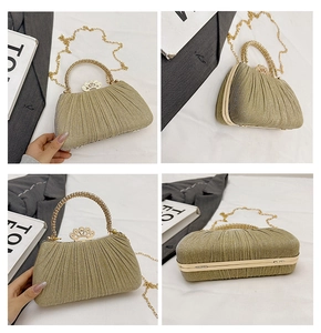 Detail of gold pleated evening clutch with crown clasp and pearl handle accents