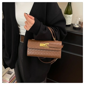 Detailed view of brown woven leather handbag with gold clasp on a luxury scene