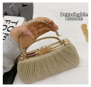 Detail of golden pleated evening clutch bag featuring a detachable beaded top handle