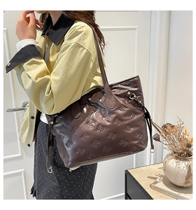 Detail view of the embossed bow pattern on this dark brown large capacity tote bag