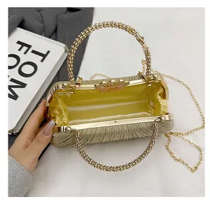 Detail of golden pleated evening bag with pearl handle and satin interior lining