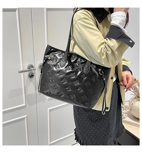 Detail of black glossy tote bag with embossed bow patterns and adjustable side drawstrings