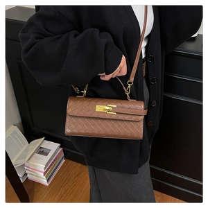 Detail of a brown woven texture handbag with golden twist lock and adjustable shoulder strap