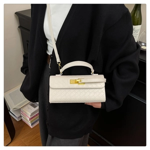 Detail of white quilted handbag with woven texture and gold metal twist lock closure