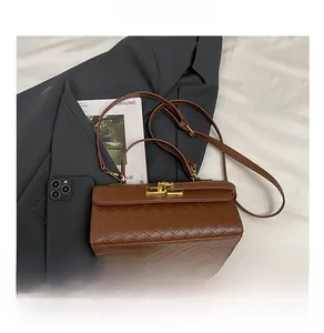 Dettaglio della borsa marrone in pelle PU intrecciata con fibbia dorata e tracolla