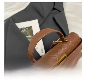 Dettaglio della pelle intrecciata e hardware dorato sulla borsa a mano marrone scuro