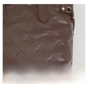 Vista dettagliata della borsa tote marrone scuro con motivi a fiocco e anello a D oro