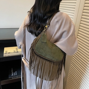 Vintage moss green dumpling bag with long fringe and golden lock on a female model