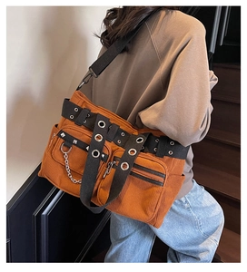 Detail of orange corduroy tote bag featuring silver chains and metal rivets decoration