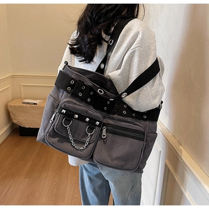 Detail of dark grey corduroy tote bag featuring punk rivets, metal chains and wide eyelet strap
