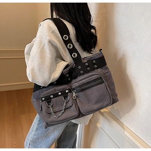 Close-up of corduroy shoulder bag with silver studs and metal grommet strap details