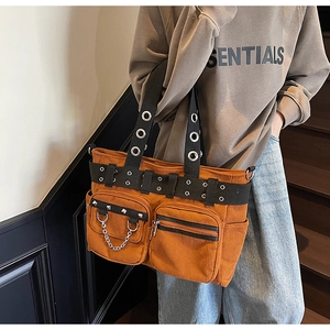 Close-up of corduroy tote bag with punk rivets, metal eyelets, and front zipper pockets