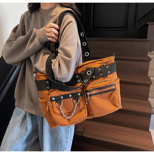 Detail of rust red corduroy tote bag showing punk rivets and metal chain accents