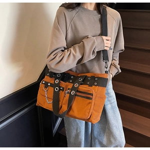 Detail of corduroy crossbody bag with punk metal rivets and decorative chains in caramel