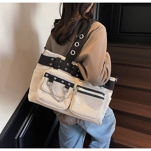 Detail of cream corduroy tote bag showing metal rivets, pockets, and silver chain straps