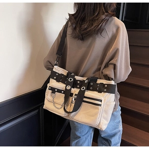 Detail of beige corduroy tote bag with punk rivets, metal chains and large front pockets