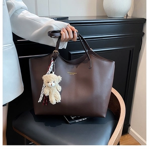 Détail du sac cabas marron foncé avec texture litchi douce et pendentif ours peluche