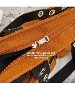 Macro shot of silver metal zipper puller and rivet detail on brown corduroy bag