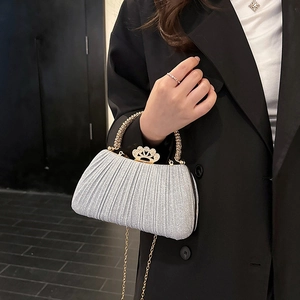 Silver glitter pleated evening clutch with crown clasp and golden metal handle shown on model