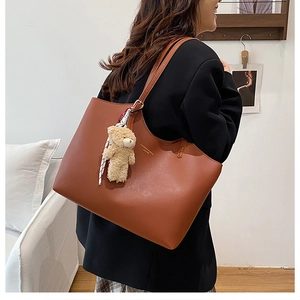 Sac cabas en cuir marron avec logo doré, breloque ours en peluche et foulard à carreaux