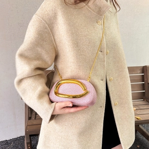 Pink glitter evening bag with gold chain strap shown on a beige wool coat over shoulder