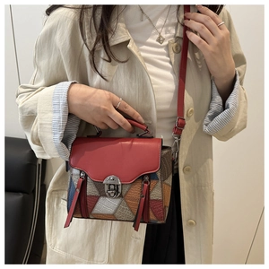 Dettaglio borsa rossa a blocchi di colore con chiusura metallica su trench beige elegante