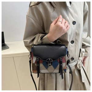 Detail of a color-block patchwork leather handbag with metal turn-lock and tassel charm