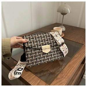 Close-up of retro tweed crossbody bag with golden lock and wide jacquard strap