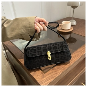 Detail of a black leopard print baguette bag featuring a shiny gold capsule lock buckle