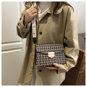 Detail of checkered crossbody bag with wide ethnic embroidered strap and gold clasp