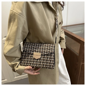 Detail of tweed crossbody bag with textured fabric, golden buckle, and wide strap