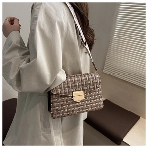 Detail of tweed crossbody bag with golden lock and wide patterned shoulder strap