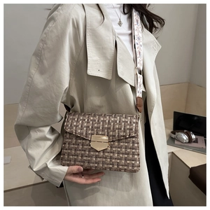 Detail of tweed crossbody bag with metallic clasp and patterned wide shoulder strap