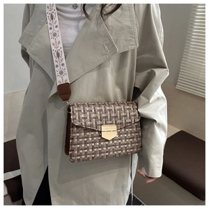 Close-up of brown woven flap bag with golden buckle and retro ethnic wide shoulder strap