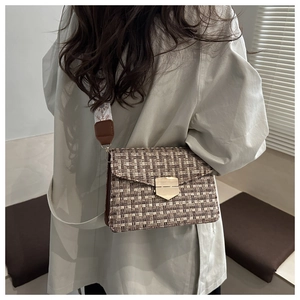 Close-up of retro tweed crossbody bag with golden shield lock and patterned wide strap