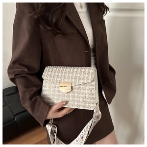 Detail of tweed crossbody bag with gold buckle and wide printed shoulder strap on model