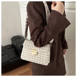 Close-up of vintage tweed crossbody bag with wide embroidered strap and gold buckle