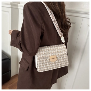 Detail of beige tweed crossbody bag with golden shield lock and wide ethnic strap