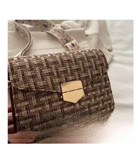 Close-up of brown tweed woven crossbody bag with vintage pattern wide strap and gold buckle