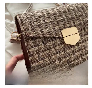 Detail of tan tweed woven crossbody bag featuring a golden buckle and leather trim