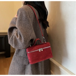 Gros plan d'un sac à main en daim rouge foncé avec des fermetures éclair en forme de cœur
